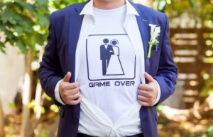 newlywed in blue costume with opened shirt showing t-shirt with funny picture of marrieds